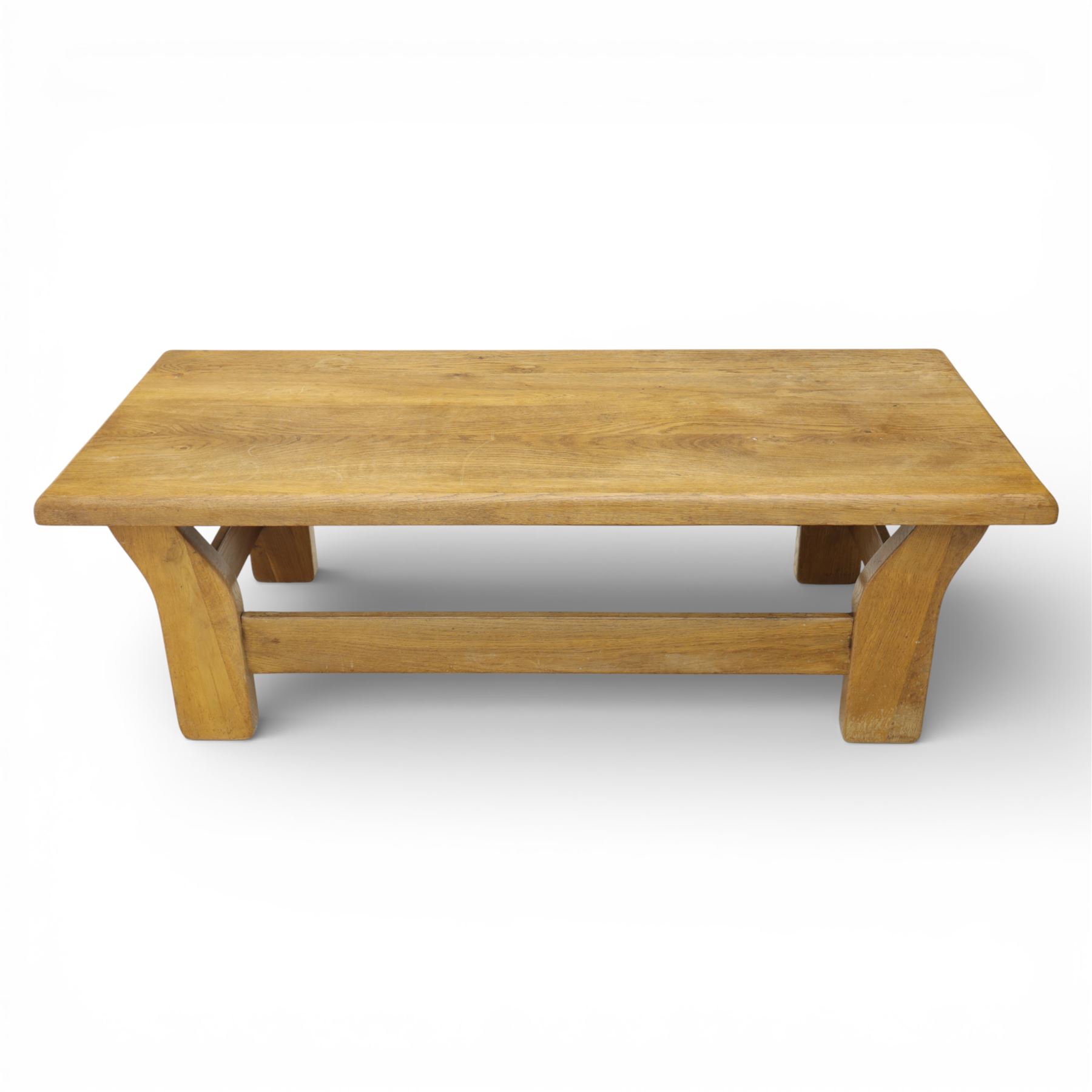 Modern oak coffee table, rectangular solid top with softly rounded edges, raised on shaped slab end supports united by a full-width stretcher
