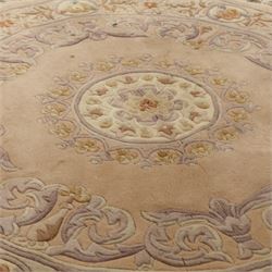 Late 20th-century circular peach-toned rug, with central floral rosette medallion surrounded by scrolling floral motifs within concentric borders, with cotton fringe perimeter 
