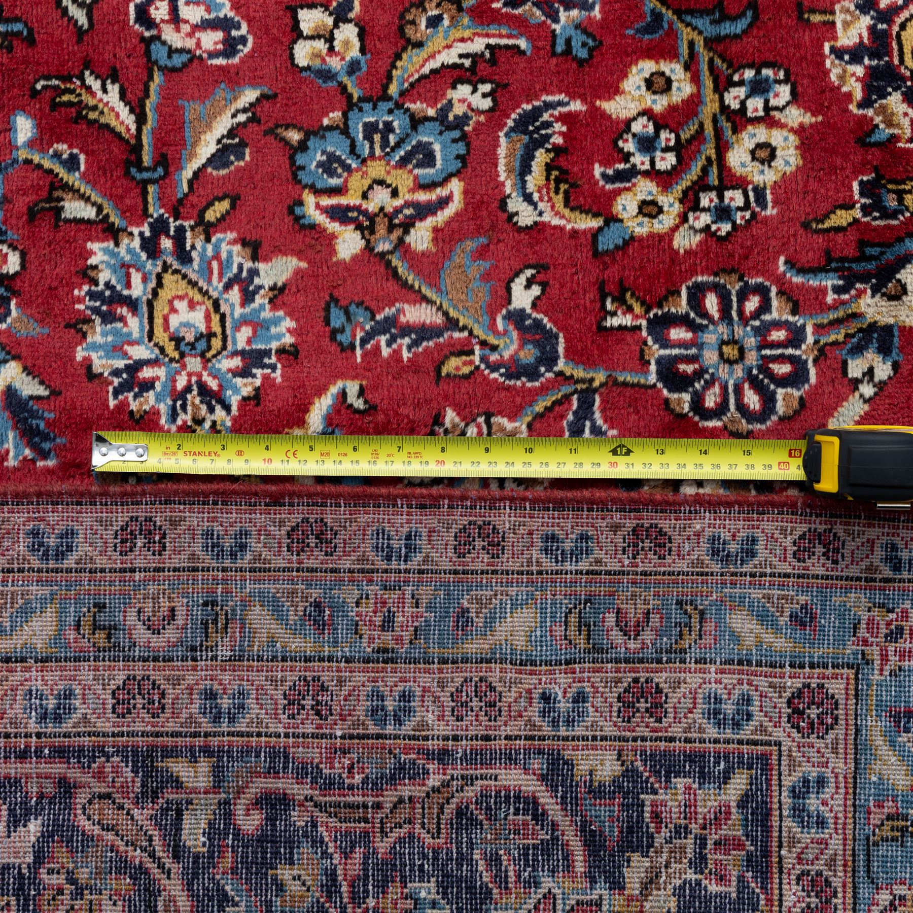 Persian Ardakan carpet, brick red field with ivory and navy central medallion, surrounded by stylised lotus blossoms and cloudband motifs, framed by rich indigo borders featuring palmettes, serrated leaves and angular vine work, woven in the city of Ardakan in central Iran