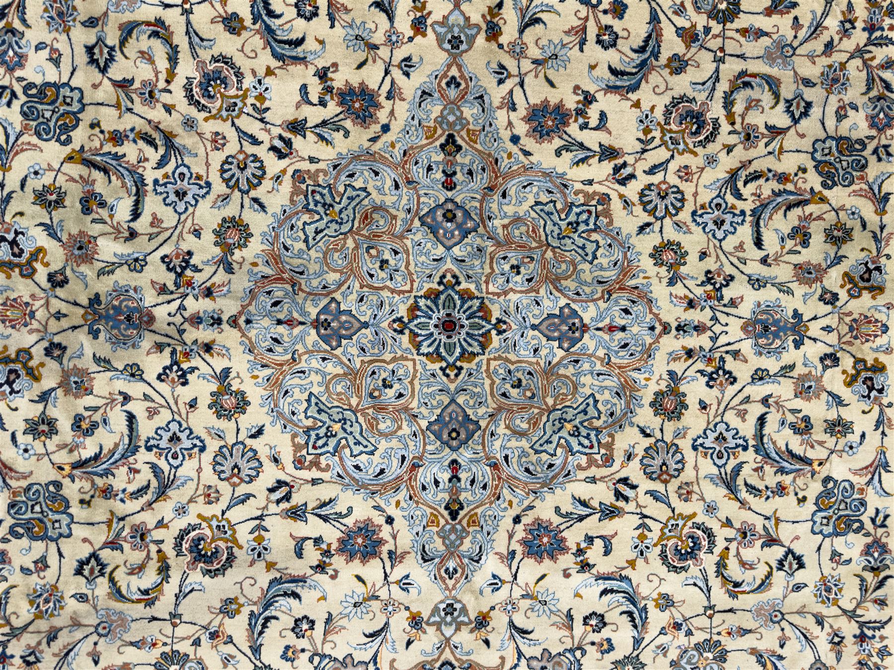 Central Persian Kashan hand-knotted carpet, ivory field with scrolling vines, palmettes, and rosettes around a cusped medallion with pendants and spandrels within a blue ground border of palmettes and flowerheads, 388cm x 300cm