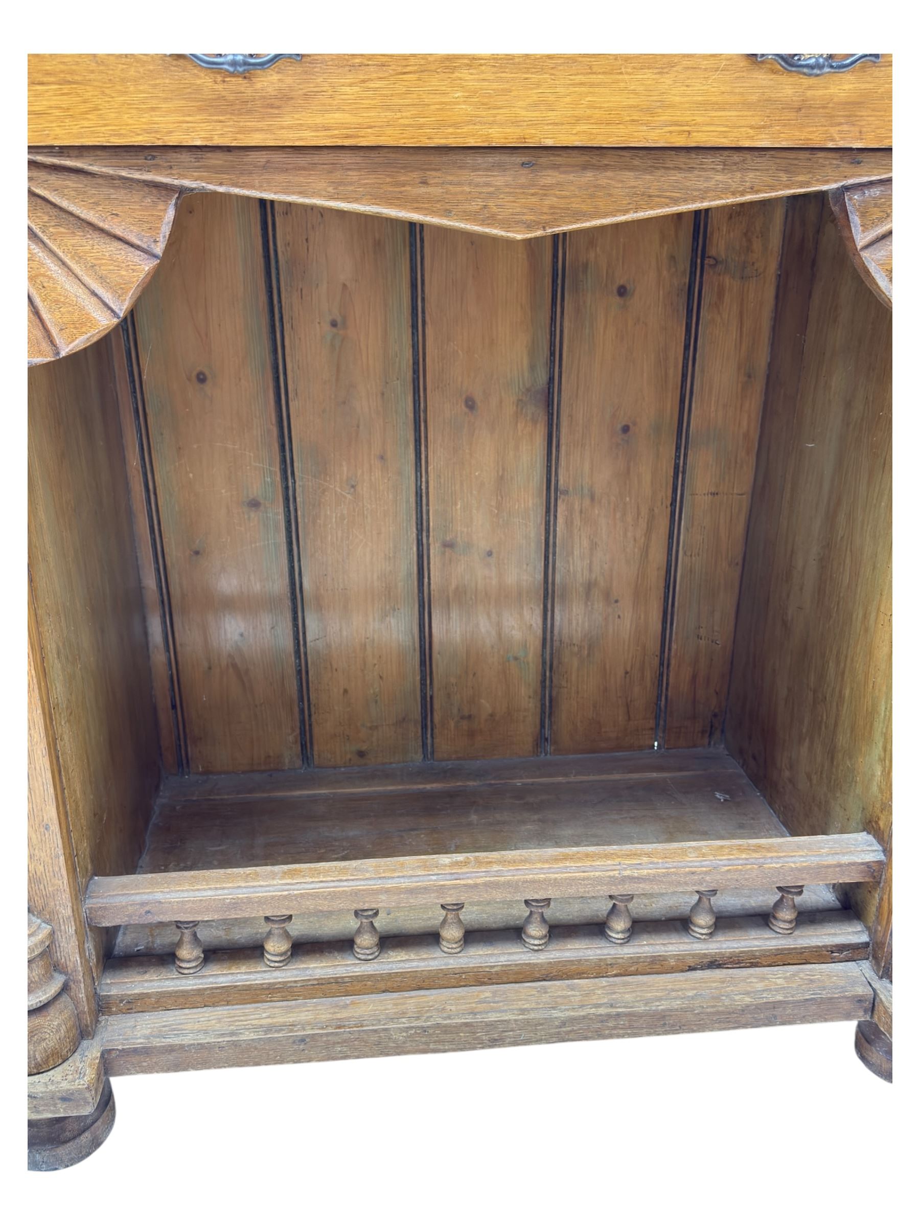Late 19th century pine dresser, the projecting cornice with dentil and spindle moulded frieze above a three-tier plate shelves, flanked by glazed doors, the base fitted with three frieze drawers over arched apron and carved floral panelled cupboard doors, raised on turned feet