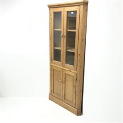 Solid pine corner cabinet, projecting cornice, two glazed doors enclosing two shelves above two cupboards, platform base