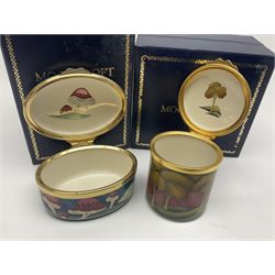 Two Moorcroft enamel boxes, the first example of oval form, decorated with mushrooms upon a blue ground, the second of circular form, decorated with trees on a red ground, each with fitted box  