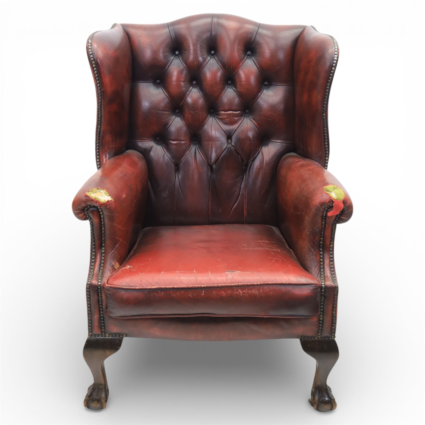 Georgian design wingback armchair upholstered in oxblood leather, the deep button upholstered back with shaped wings and out-scrolled arms, close nailhead trim to the edges, over a loose seat cushion, raised on cabriole front supports terminating in claw and ball feet