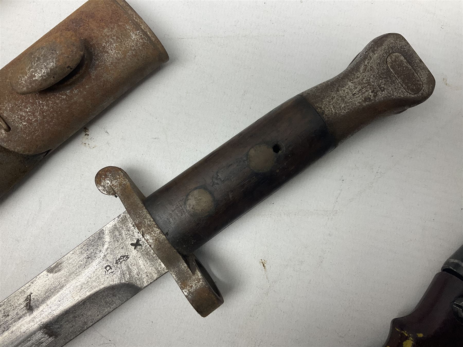 British No 7 MKI knife bayonet with 20cm single edged fullered clipped point blade;  blackened steel, large muzzle ring cross-guard; blackened swivelling pommel marked 'F5H'; red Tufnol composite grips; in blackened steel scabbard L33cm overall; British Pattern 1888 bayonet with scabbard; and German Ersatz bayonet with scabbard (3)