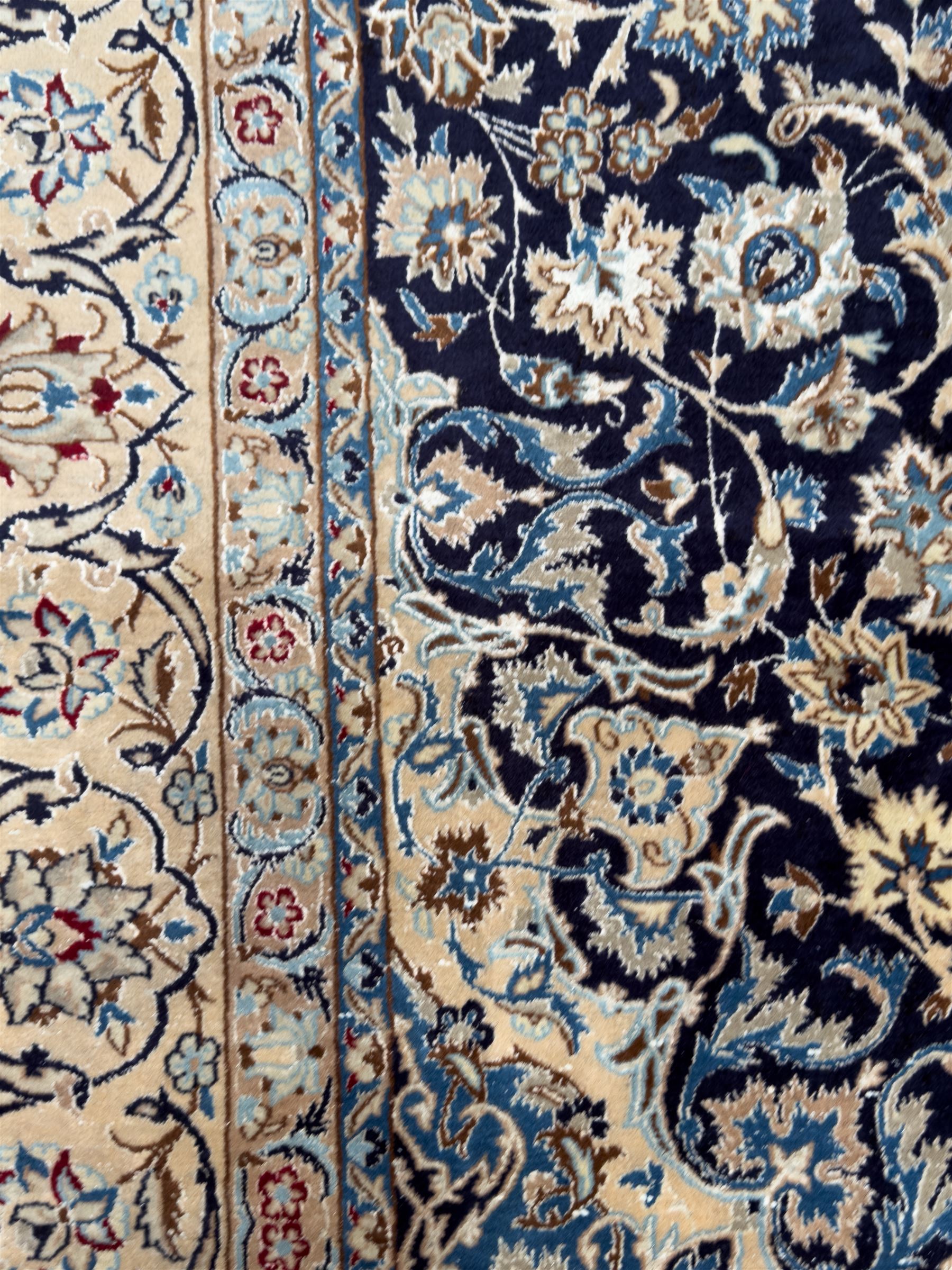 Central Persian Nain carpet, the deep blue field with finely drawn scrolling palmettes and flowering vines around a central ivory and sky blue rosette medallion, enclosed by an ivory border of interlaced floral arabesques and lotus forms between multiple guard stripes, from the region of Nain