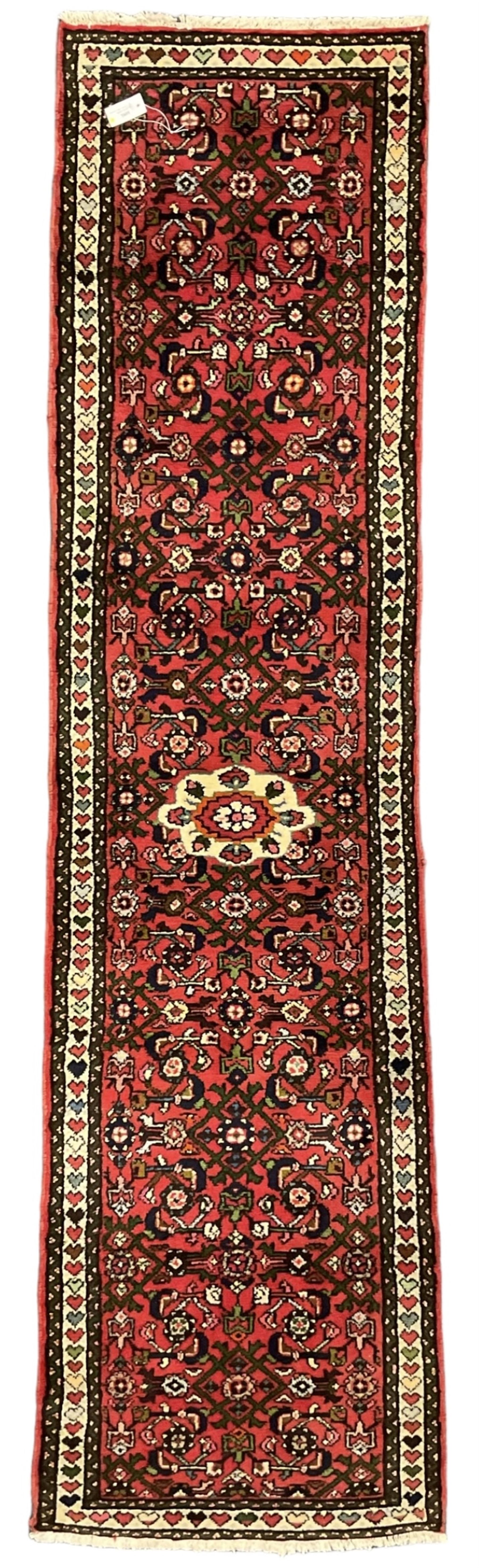 Persian red ground runner, decorated with large Herati motifs and shaped central medallion, the guarded border decorated with repeating heart motifs