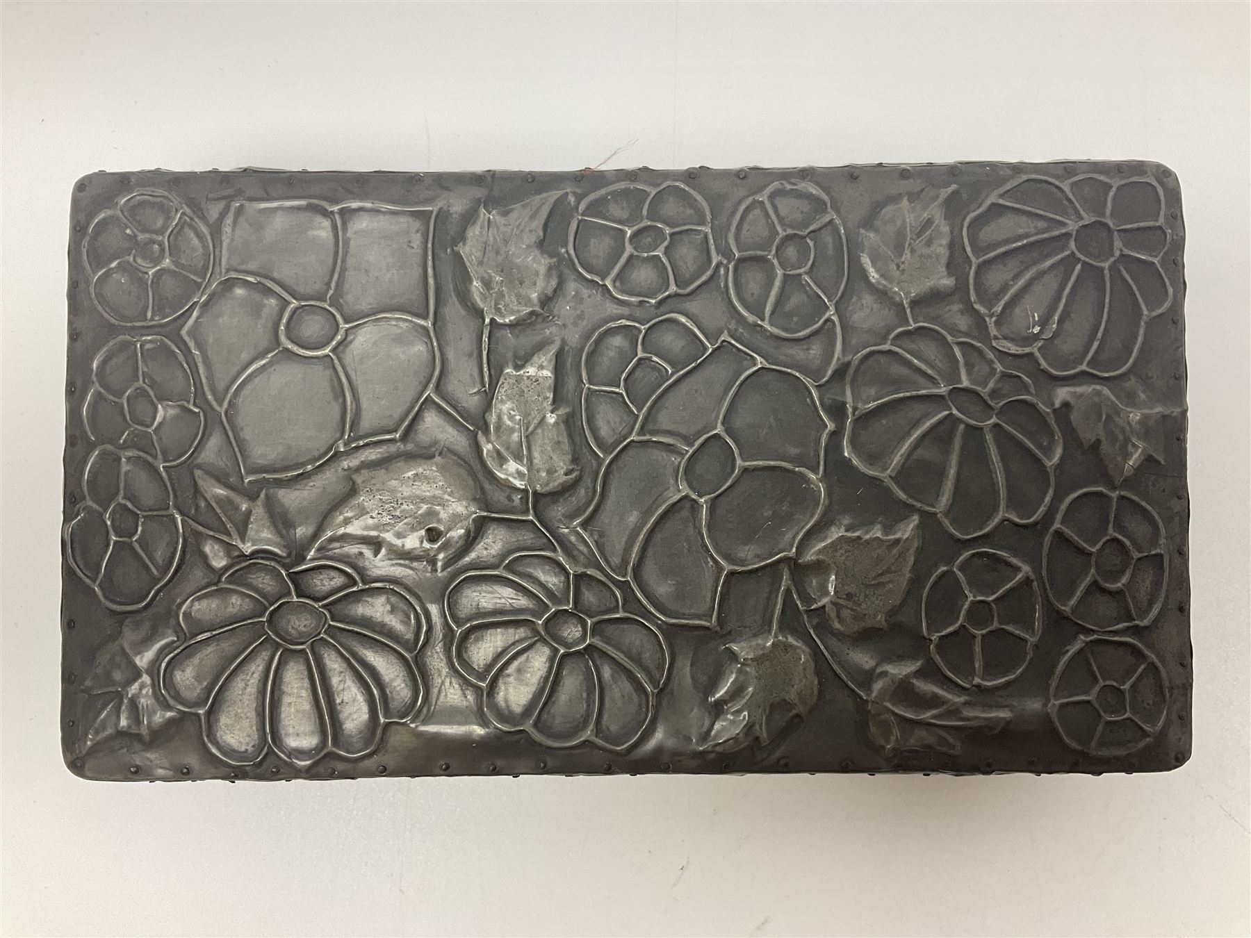 Liberty & Co Tudric pewter cigarette box, of plain rectangular form, with planished decoration to the slightly domed cover, opening to reveal a softwood interior, stamped Made in England 01234 Tudric Solkets beneath, together with another cigarette box, with applied pewter panels repousse decorated throughout with flower heads and leaves, with compartmentalised softwood interior, largest H5.5cm, W23cm