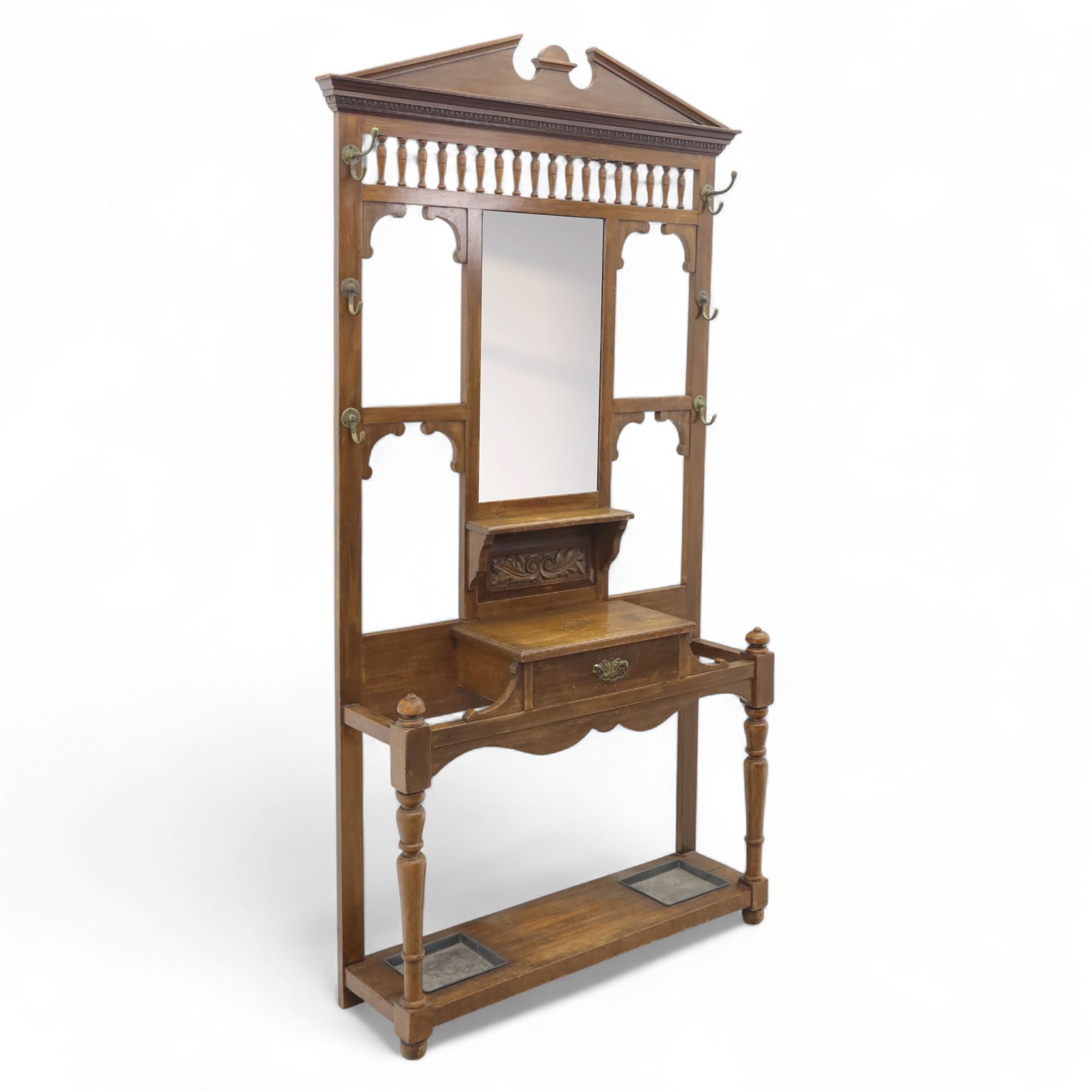 Edwardian walnut hall stand, the shaped pediment above turned spindle gallery and bevelled mirror, fitted with brass double coat hooks, single drawer with cast handle and carved frieze, flanked by turned supports, lower platform fitted with twin metal drip trays