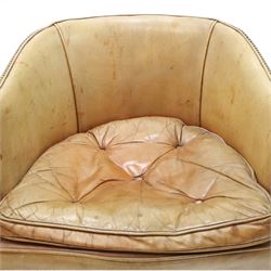 Early 20th century Georgian design mahogany framed desk or club armchair of tub form, with turned pilaster arm supports and legs with rear splayed supports, upholstered in faded tanned leather with loose seat cushion