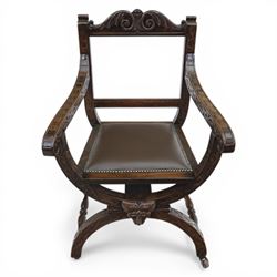 Late 20th century stained beech Savonarola chair, the carved crest rail and open arms above an upholstered leather seat, raised on an X framed base with carved foliate and mask decoration, joined by turned stretcher and ending in castors