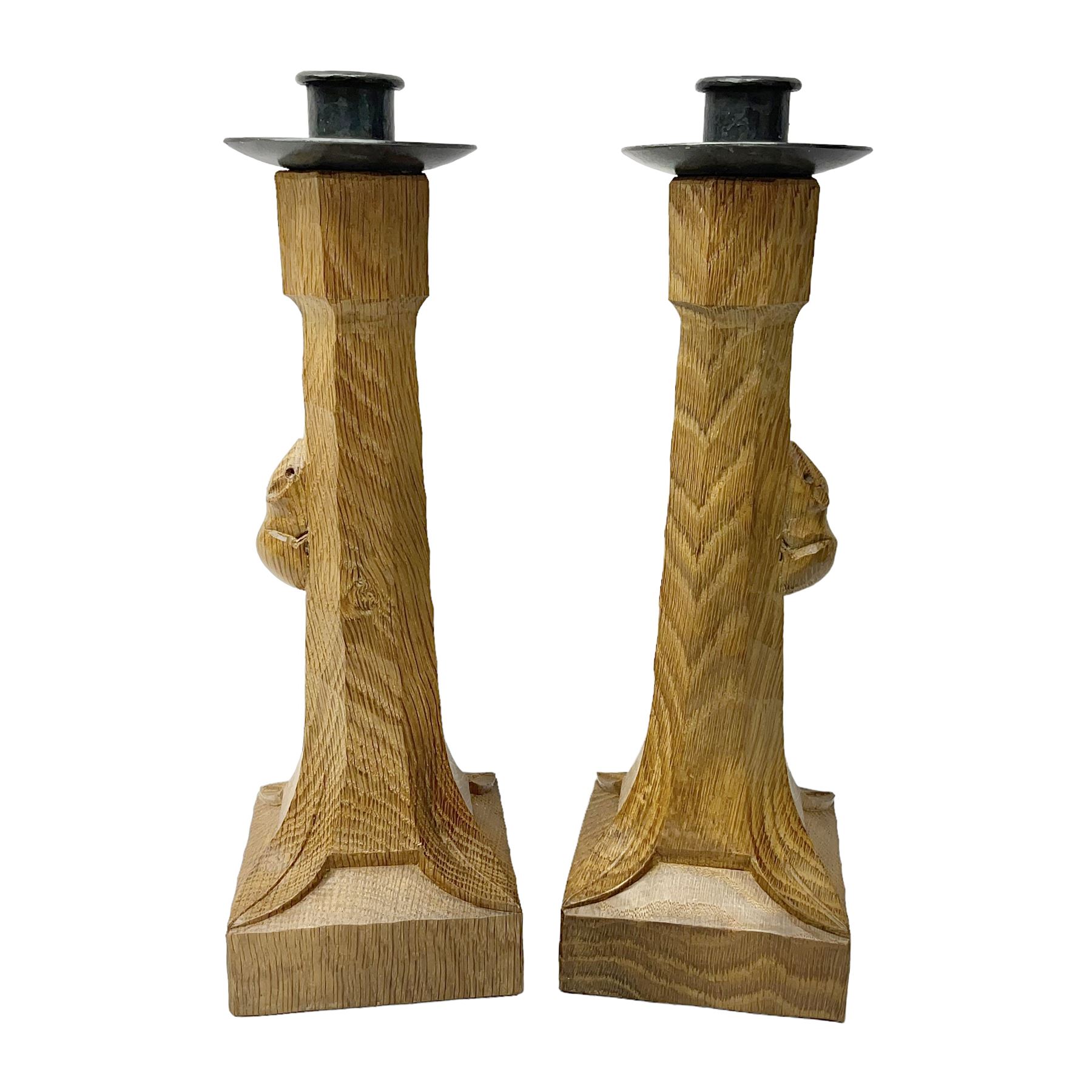 Mouseman - pair of tooled oak candlesticks, wrought iron sconce with drip tray over tapered octagonal column carved with mouse signature, terminating to stylised leaf carved square base, by the workshop of Robert Thompson, Kilburn
