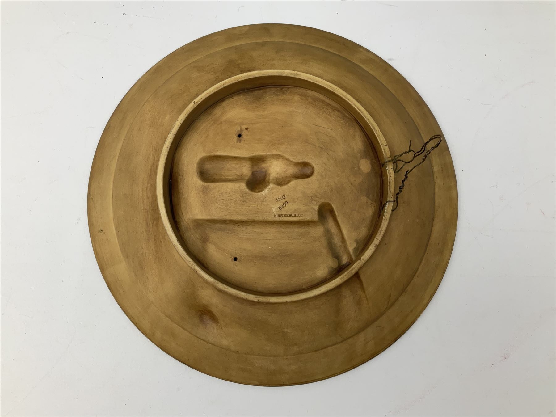 Two oil painted chargers decorated with joyful gentleman, both signed W Stanley, together with a Musterschutz charger decorated in high relief