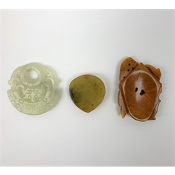Two Russet carved jade pendants, one with zoomorphic detail, the other with floral detail, largest H6cm, together with a celadon jade pendant or bi disc, also with carved zoomorphic detail, D5cm. (3).