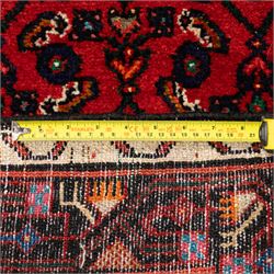 North West Persian Malayer runner, madder red field decorated with an all-over design of stylized herati motifs in shades of indigo, ivory, and green within ivory and dark blue borders of angular vine and rosette design, with cotton fringe ends 
