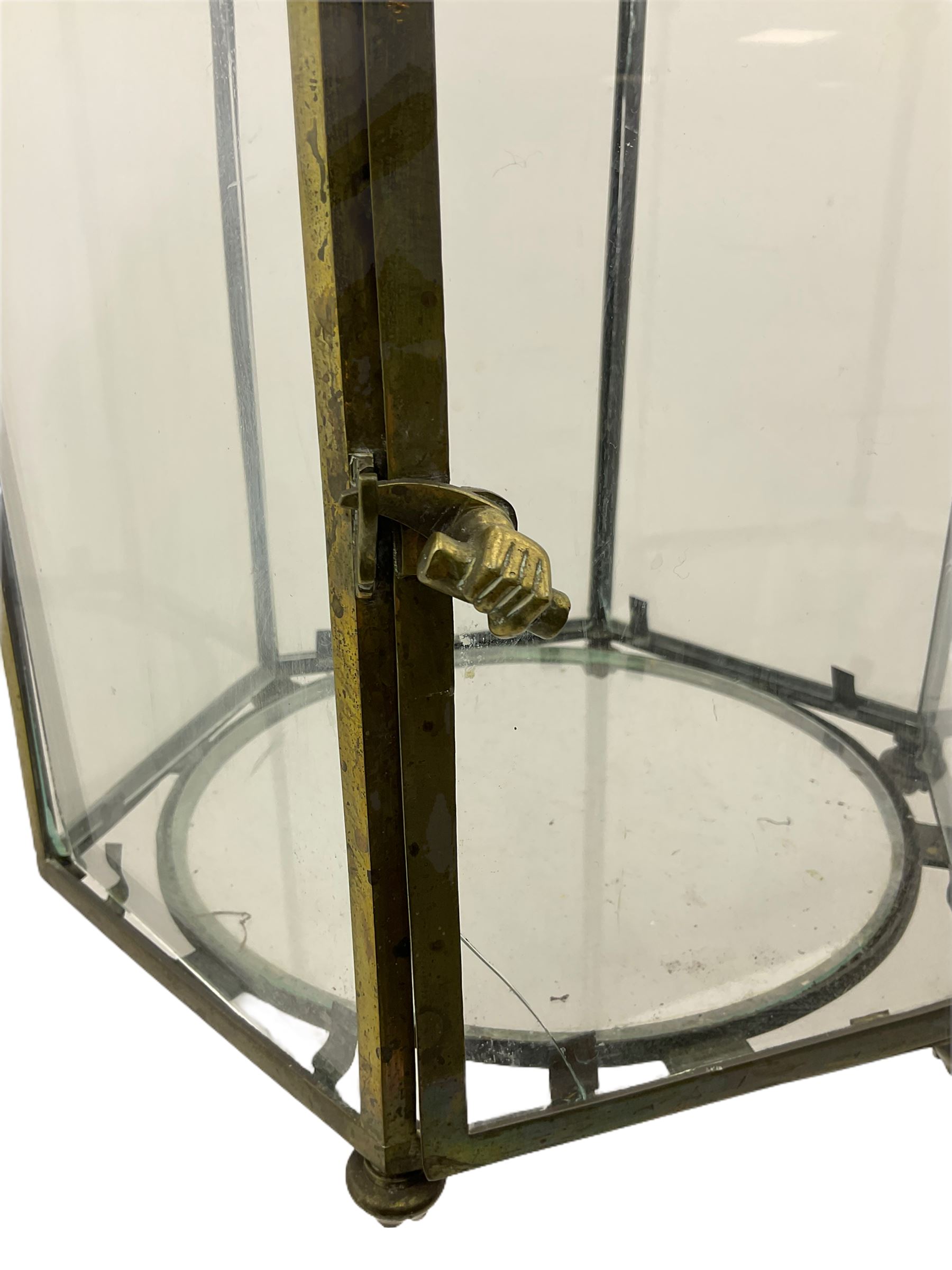 19th century brass and clear glass hexagonal hall lantern, with scrolling wire work open domed top over six arched panels, including a hinged door, the base enclosed with a circular glass panel on turned feet, H64cm