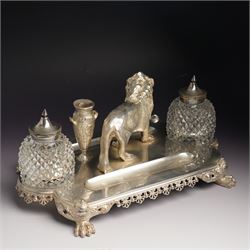 19th century Walker & Hall, silver plated inkstand, oblong and on four paw feet, the border decorated with pierced shell design, each side with a pen-rest, with two cut-glass bottles and central lion and urn finials, engraved to the front with an inscription, H15cm, L30cm