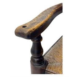 Early 19th century ash armchair, the back with winged spindles extending from a shaped top rail, above a splat of two rows of vertical spindles, with curved arms and a rush seat, raised on turned supports united by double stretchers terminating in castors