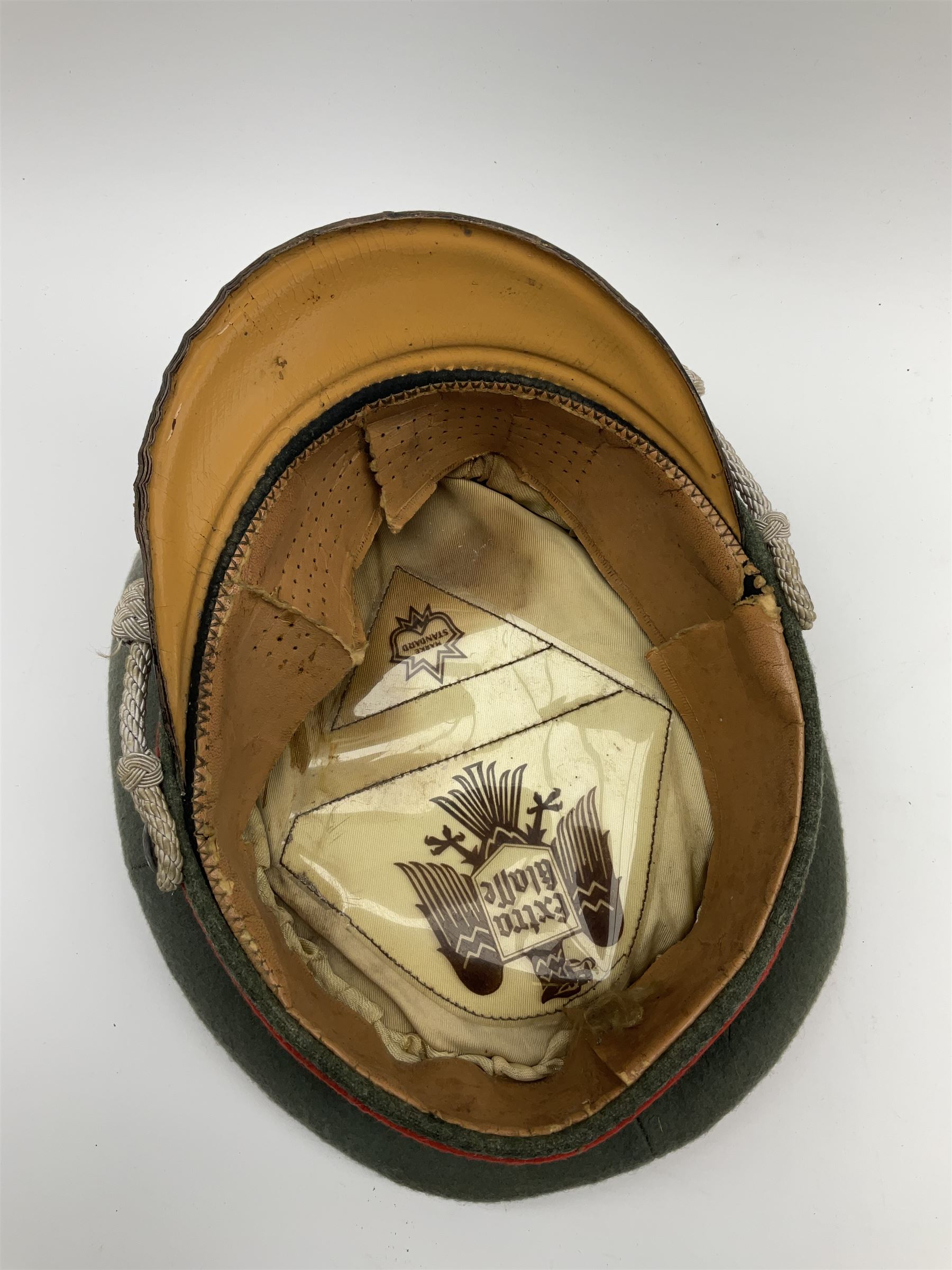 WW2 German Army Artillery officer's peaked cap, red piping to the crown and bordering the central band, zinc eagle and aluminium cockade insignia, officer's bullion chin cords, interior retains original sweatband and lining has tailor's celluloid diamond with 'Extra Klasse' logo and 'Marke Standard'