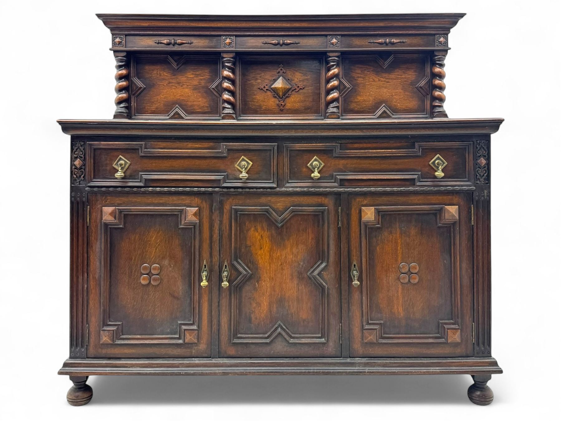 Jacobean-style oak dresser base with two frieze drawers above three cupboards with panelled and moulded decoration, fitted with drop handles, supported on bun feet, circa 1900