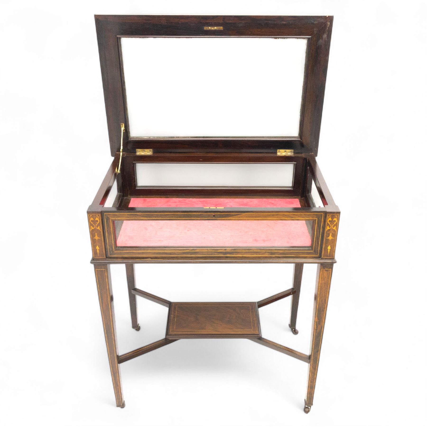 Edwardian rosewood bijouterie cabinet, the hinged rectangular top with line inlay enclosing a velvet lined interior, upon slender tapering legs inlaid with satinwood foliate marquetry decoration, with stretchers united by an under tier, raised on castors 