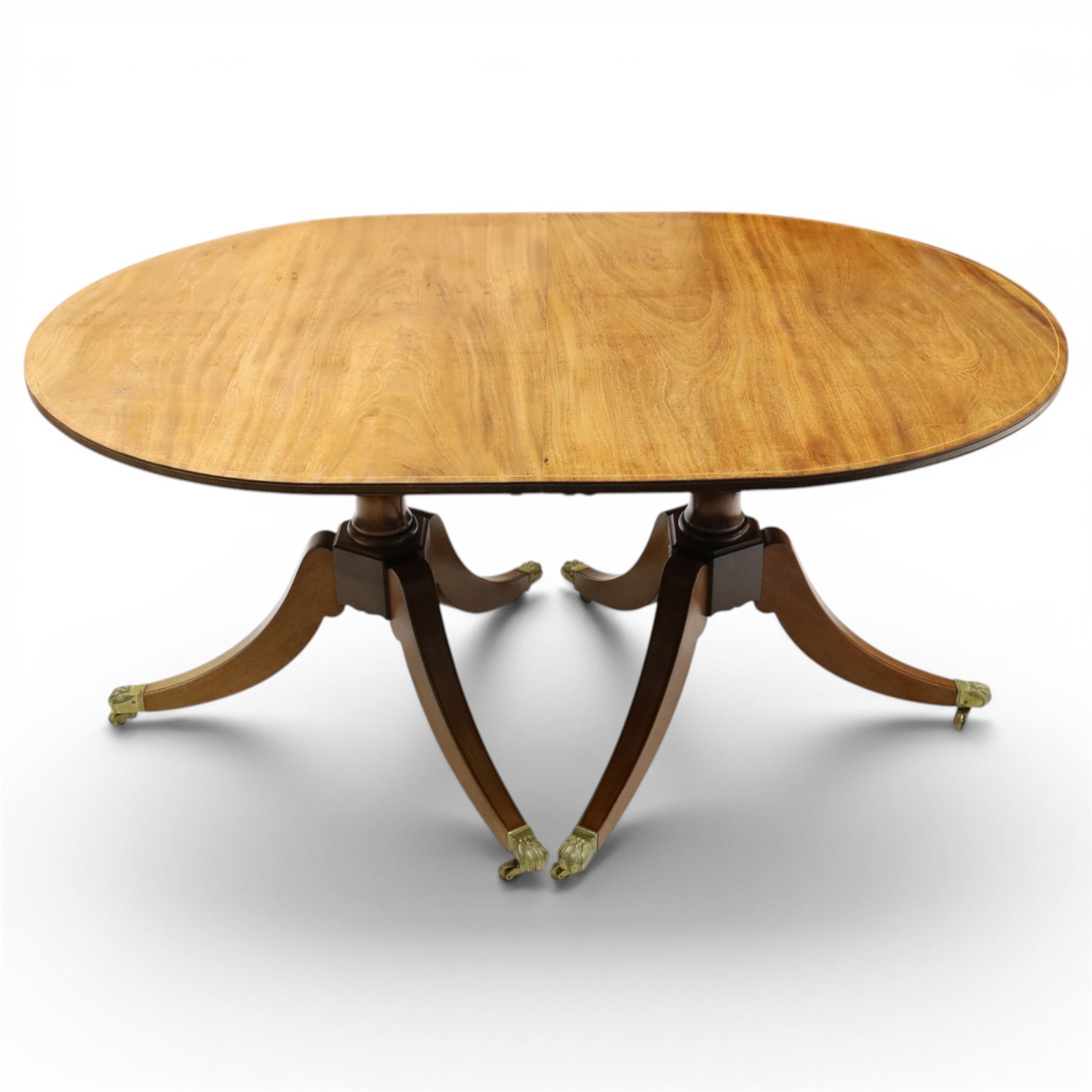 Acornman - mahogany twin pillar extending dining table, strongly grained top with inlaid edge, raised on a ring turned baluster column, above three swept supports terminating in brass paw feet above castors, two additional leaves extending the table to 242cm, with signature carved acorn, by the workshop of Alan Grainger of Brandsby