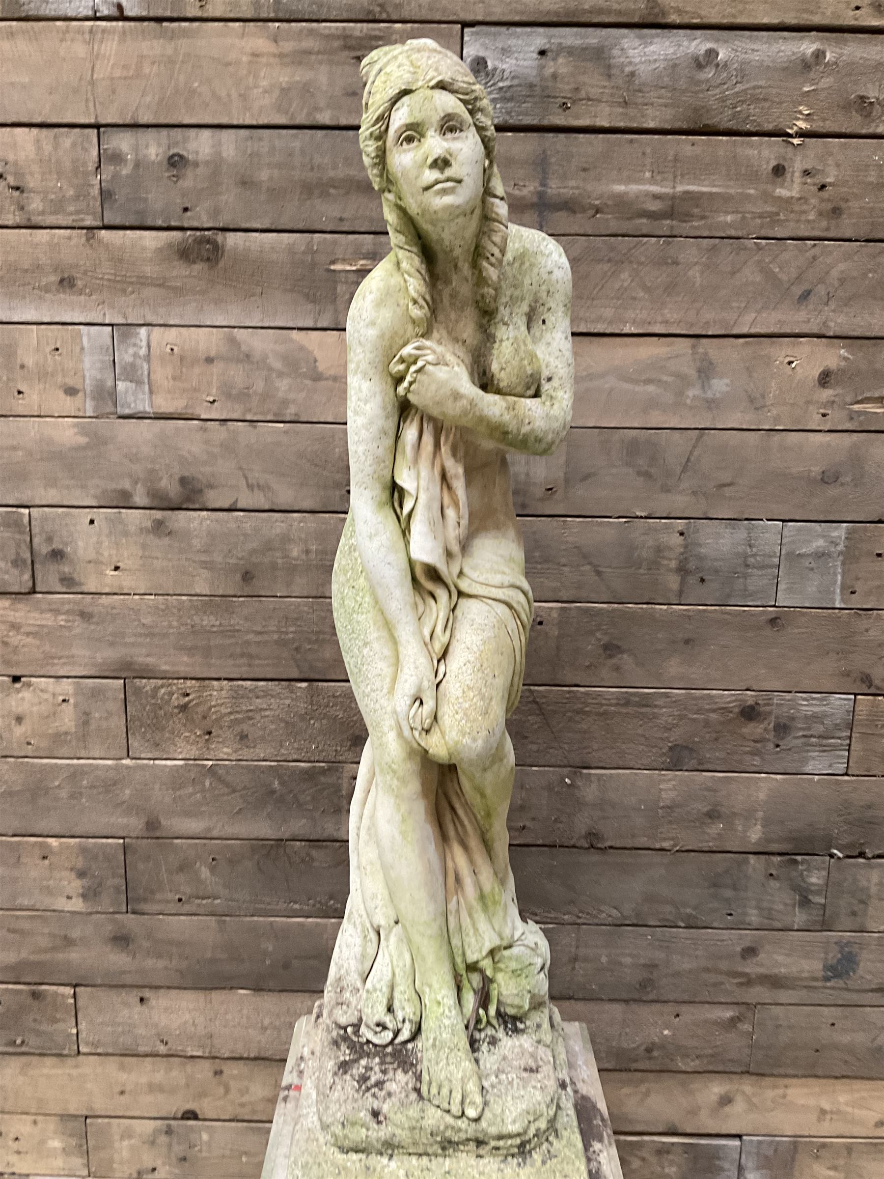 Cast stone garden figure of a bathing lady, raised on square plinth