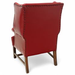 20th century Georgian design mahogany framed wingback armchair upholstered in red leather, shaped back flanked by winged sides and down-swept arms raised on squared legs 