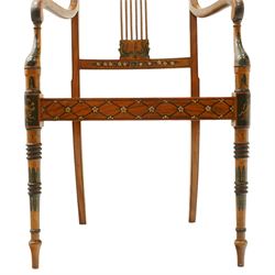 Late 19th century Adam Revival painted and parcel-ebonised satinwood open armchair, the cresting rail centred by a painted panel depicting putti holding garlands, within draped swag ornament and moulded ribbon-twists, over a pierced vertical splat with gilt beaded detail, the downswept arms and caned seat above a painted lattice and floral frieze, raised on ring-turned tapering front supports with musical instrument painted panel and acanthus leaves