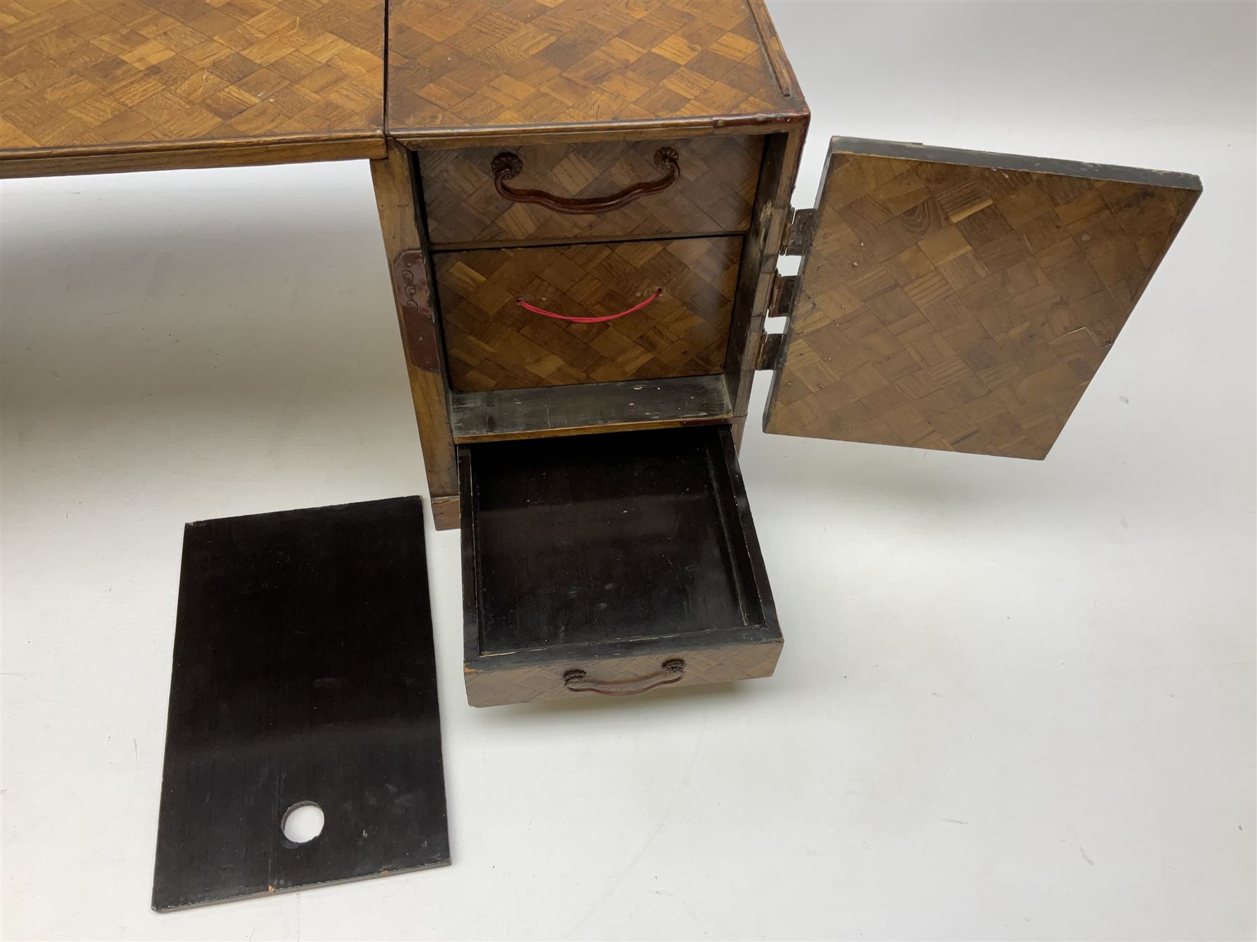 Japanese miniature kneehole desk decorated with parquetry inlay, the loose leaf top resting on one pedestal cabinet with four drawers, and another with hinged cupboard door opening to reveal two interior drawers above a lower drawer, H26cm, W68.5cm D24cm
