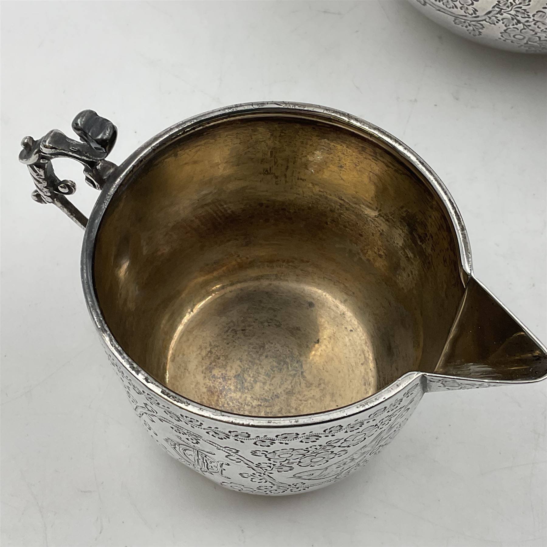 Late Victorian silver bachelors three piece tea service, comprising bullet shaped teapot, open sucrier and milk jug, each engraved with monogram surrounded by birds upon and amidst a blossoming vine, the teapot with scroll capped curved wooden handle and wooden finial to cover, hallmarked Wakely & Wheeler, London 1890, teapot including handle H12cm, sucrier H5.5cm 
