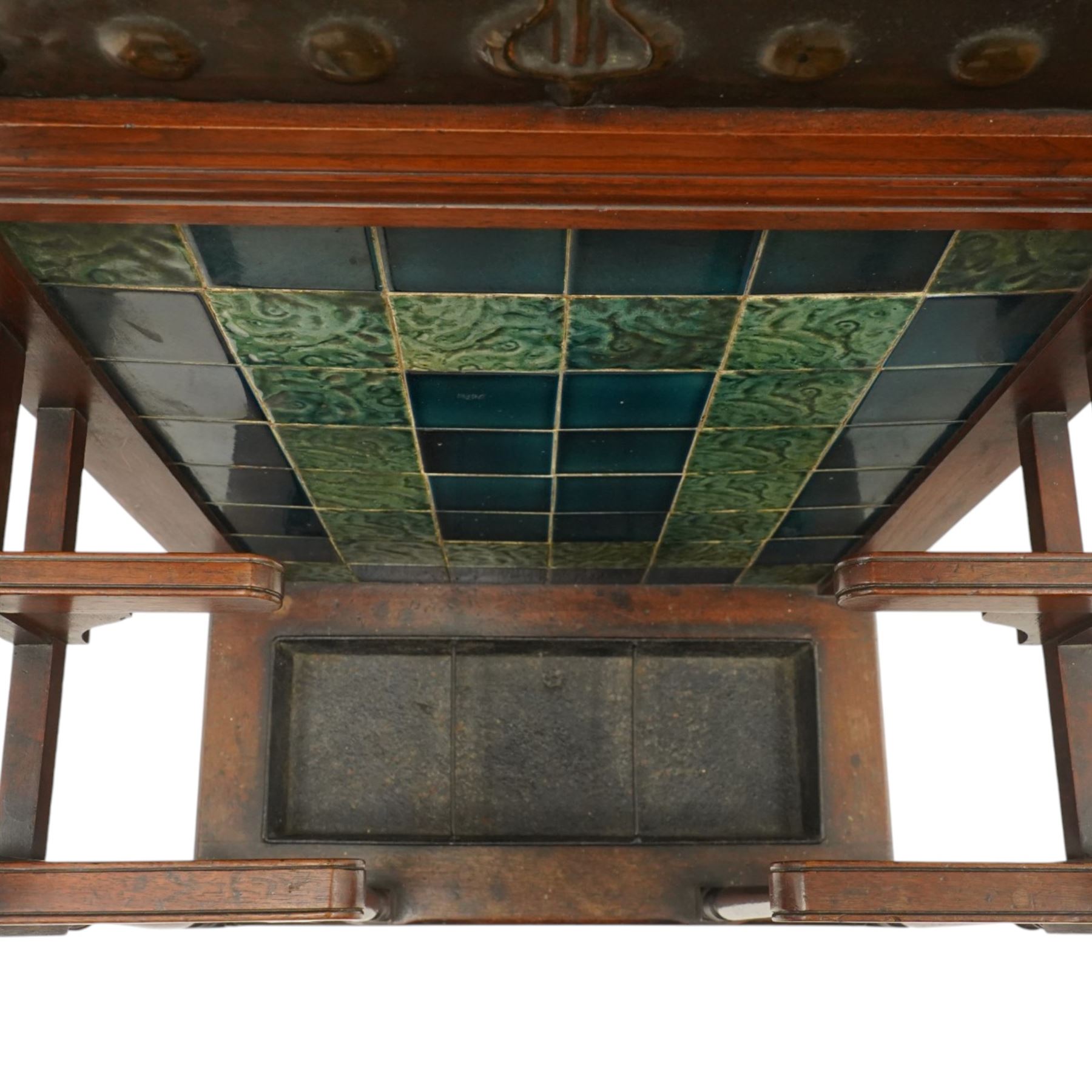 Shapland & Petter of Barnstaple - Arts & Crafts mahogany tile-backed umbrella or stick hall-stand, model no.114, the shaped back with single shelf over an Art Nouveau embossed patinated copper panel and turquoise tiled back, with turned supports and dividers over inset metal drip tray

Notes: A comparable Shapland & Petter stick stand of this model is recorded in Daryl Bennett, Shapland & Petter Ltd of Barnstaple, Museum of Barnstaple and North Devon, p.84, cat. no.5.37, and the model is also listed in Bennett, Liberty’s Furniture 1875-1915, p.298, cat. no.8.6. Examples of this model are known to have been retailed by Liberty & Co.