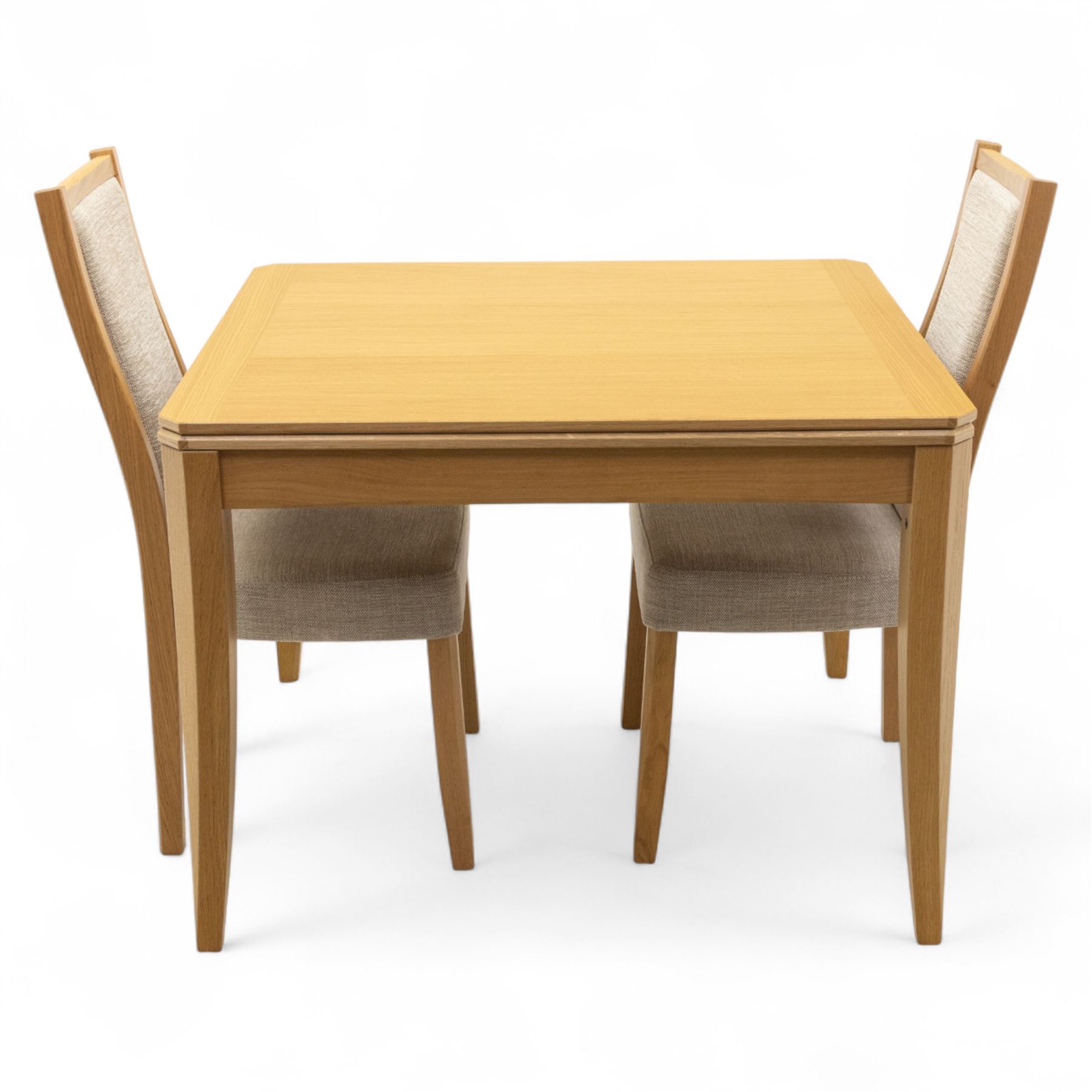 Ercol - light oak ‘Artisan’ rectangular dining table with chamfered top extending fold over top and tapered legs, together with two matching high back dining chairs upholstered in textured beige fabric (Chairs H 98cm, W 47cm, D 52cm)