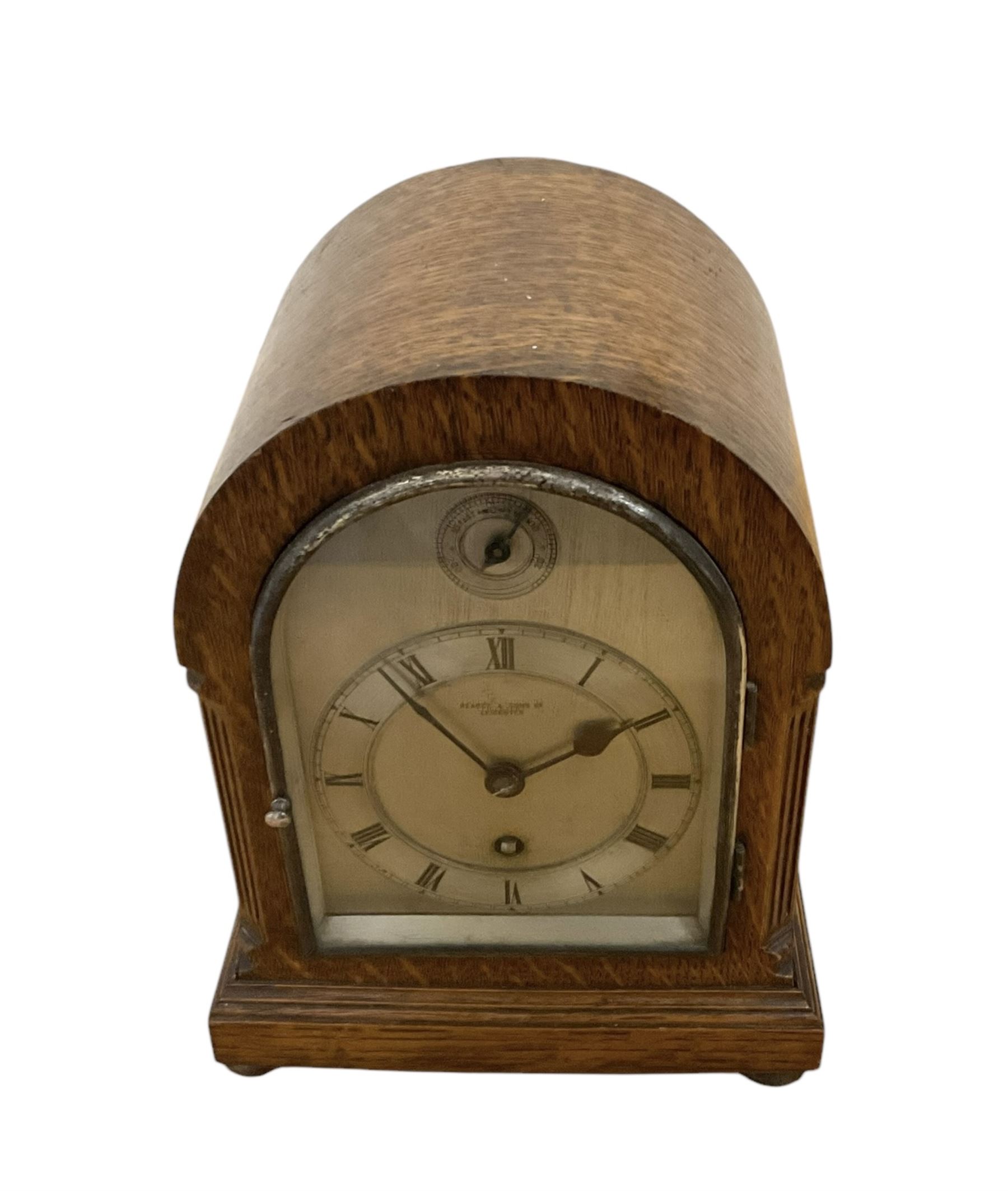 German- early 20th century oak cased 8-day mantle clock, with a round top, side frets and conforming glazed door to the dial, single sheet silvered dial with a silvered chapter and fast/slow regulation dial, Roman numerals, minute track and spade hands, going barrel movement with a lever platform escapement. With Key. 