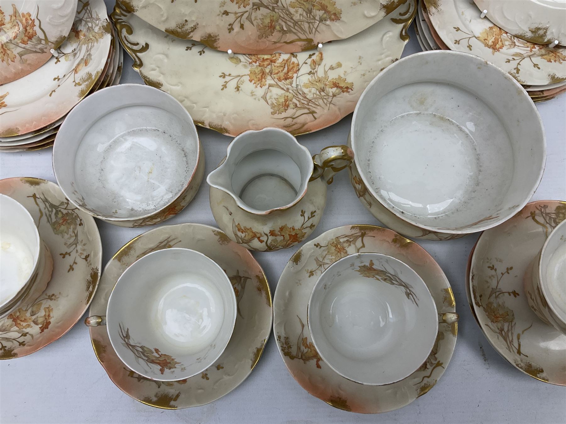 Early 20th century Limoges part tea service, decorated with floral sprays and gilt on merging peach and white ground, comprising six teacups, twelve side plates, six smaller plates, milk jug, open sucrier, slop bowl and two cake plates, many marked R Delinieres Limoges D&C France to base