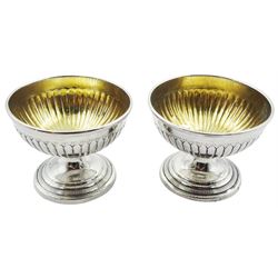 Two Georgian silver open salts, each with part fluted bowl with gilt interior, upon circular stepped pedestal base, hallmarks worn and indistinct, H5.5cm D7cm, approximate weight 3.68 ozt (114.5 grams)