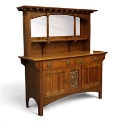 Art Nouveau oak mirrored sideboard, in the manner of Liberty's London, the raised back fitted with bevelled mirror plates divided by turned supports beneath a projecting cornice, above two drawers and panelled cupboard doors, the central panel applied with stylised floral carved panel, raised on shaped feet