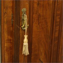 Edwardian walnut triple wardrobe, shaped broken-arch pediment over three doors comprising central mirrored door flanked by moulded raised and fielded panelled doors, interior fitted with hanging space and a bank of three open drawers above three brass recessed-pull drawers, on moulded plinth base