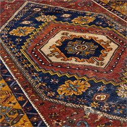 Turkish Anatolian wool rug, central stepped medallion on dark blue lozenge field, red spandrels with stylised hooked motifs, ochre border decorated with repeating geometric motifs and guard stripes