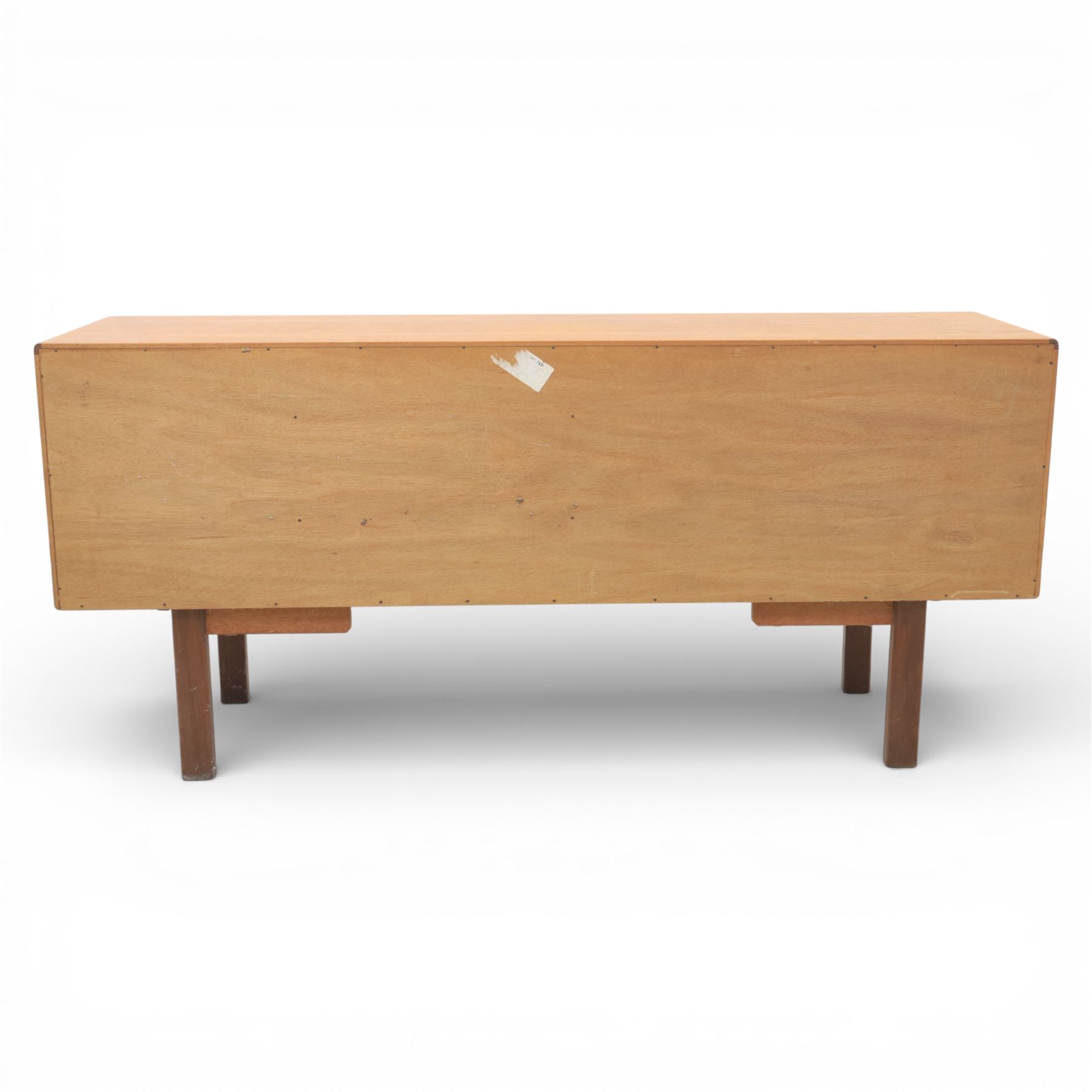 G-Plan - ‘Brasilia’ teak sideboard, rectangular top with moulded edge above a central bank of four drawers flanked by cupboard doors with carved sculptural handles, raised on tapering supports
