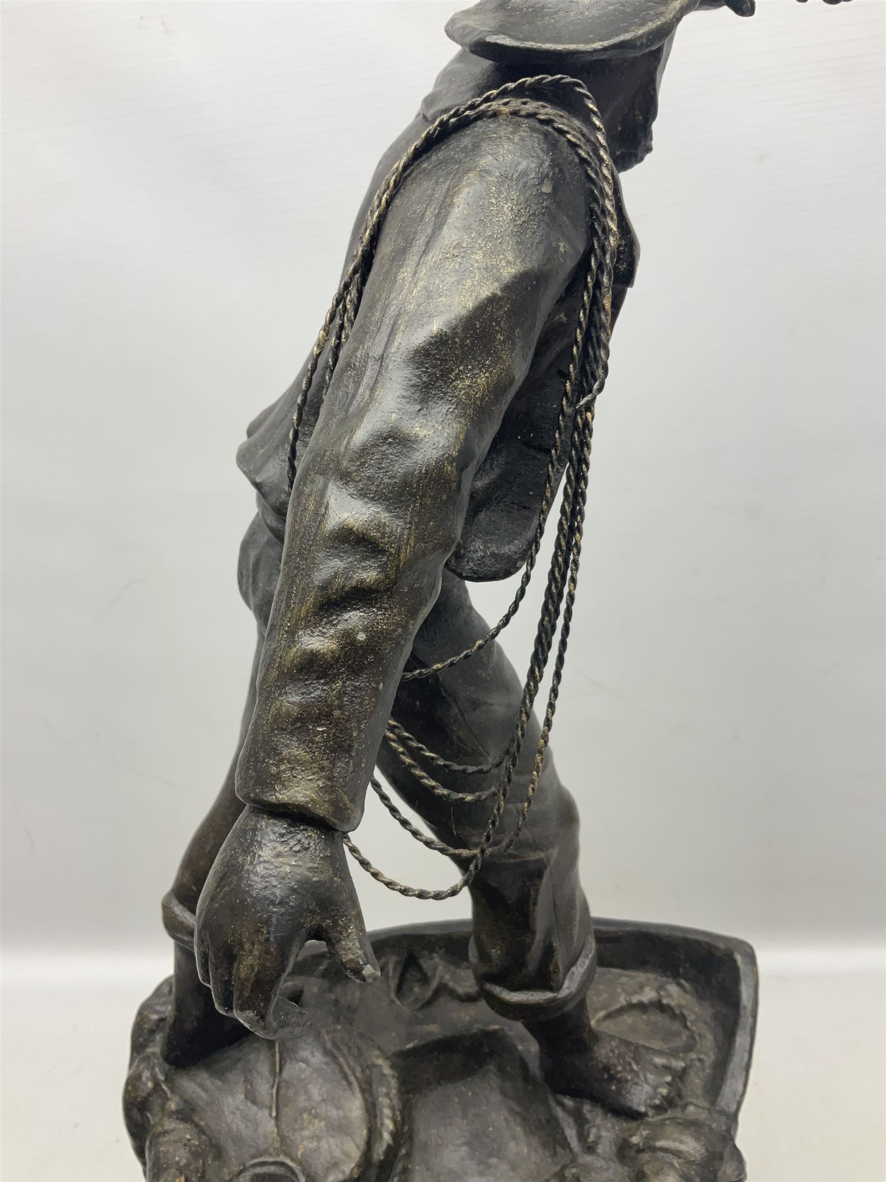 Early 20th century spelter effect figure of a sailor standing in the bow of a boat scanning the horizon, on a simulated rock base with a plaque entitled 'Rescue', base fitted with a timepiece clock movement and two-part dial, with pierced hands, gilt dial centre and ivorene chapter ring written in Arabic numerals, German HAC spring driven going barrel movement wound from the front; with pendulum H65.5cm
