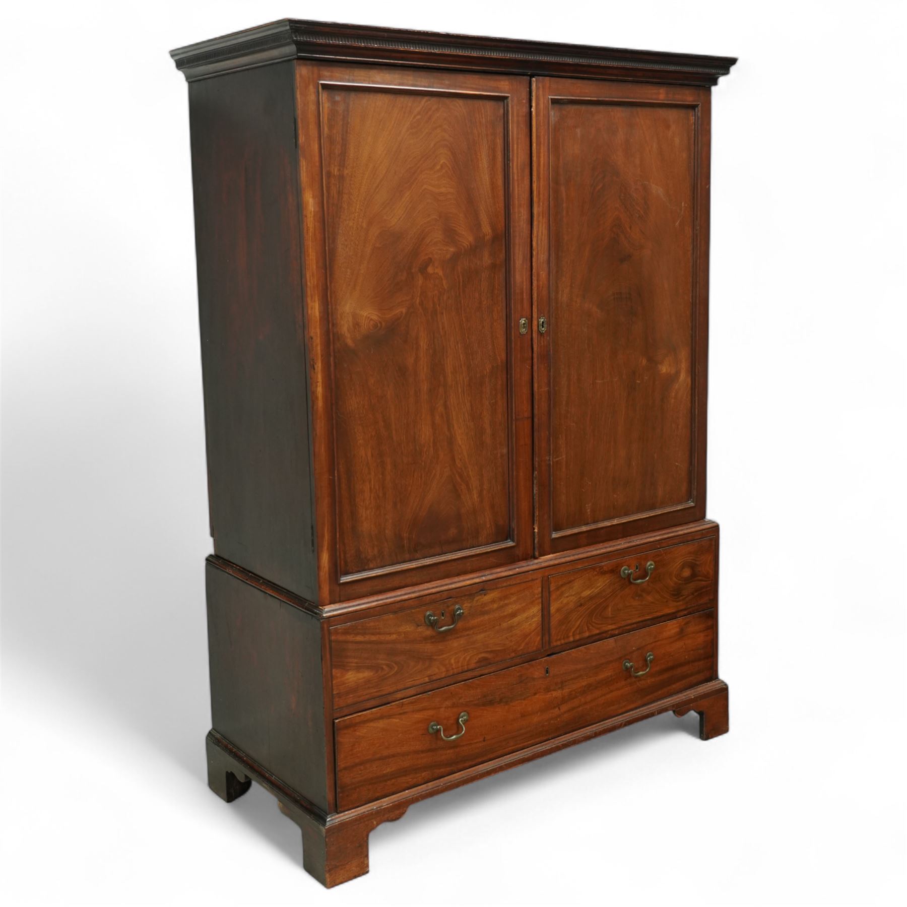 George III mahogany linen press, dentil moulded cornice over a pair of panelled doors enclosing a later fitted interior, lower section with two short over one long cockbeaded drawer, brass swan neck handles, shaped bracket feet