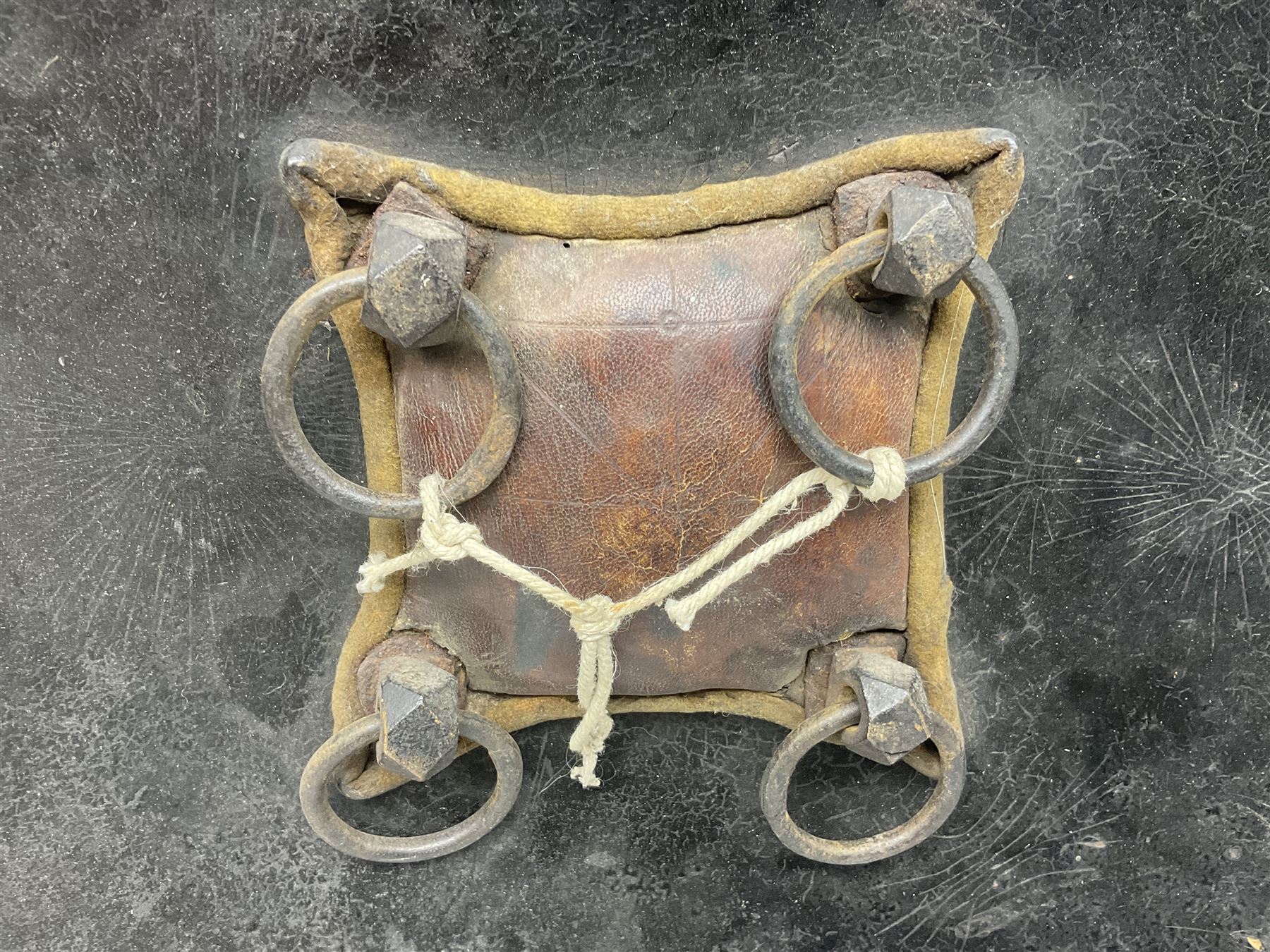 Indian black lacquered hide shield/dhal, of circular convex form with strongly outward-turned brim, fitted at its centre with four metal bosses, each of hemispherical form, with traces of silvered foliate decoration, the bosses corresponding on the inside with four iron rings for enarmes D49cm