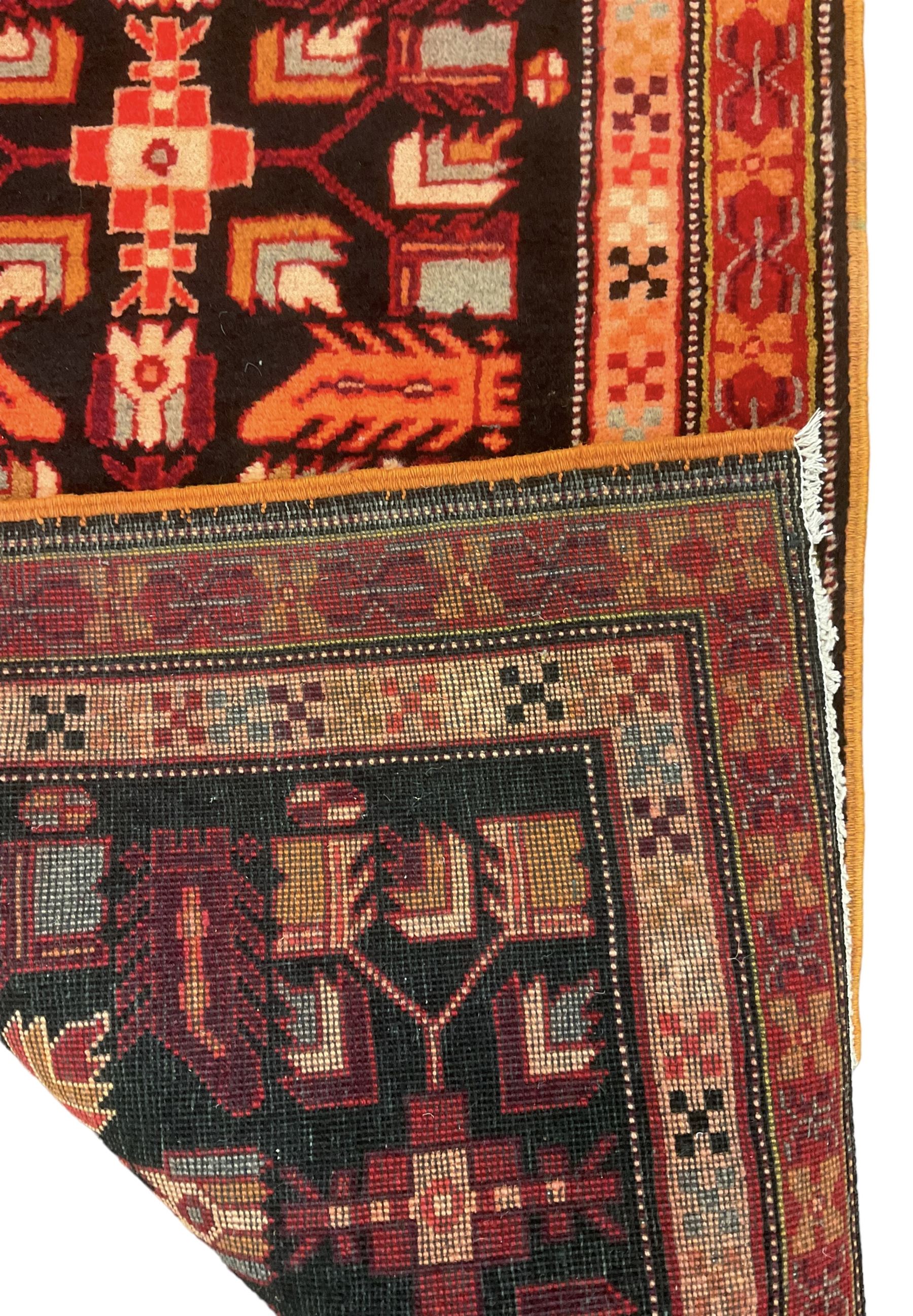 North West Persian Heriz runner, dark indigo ground field decorated with Herati motifs, peach and red borders with geometric design 