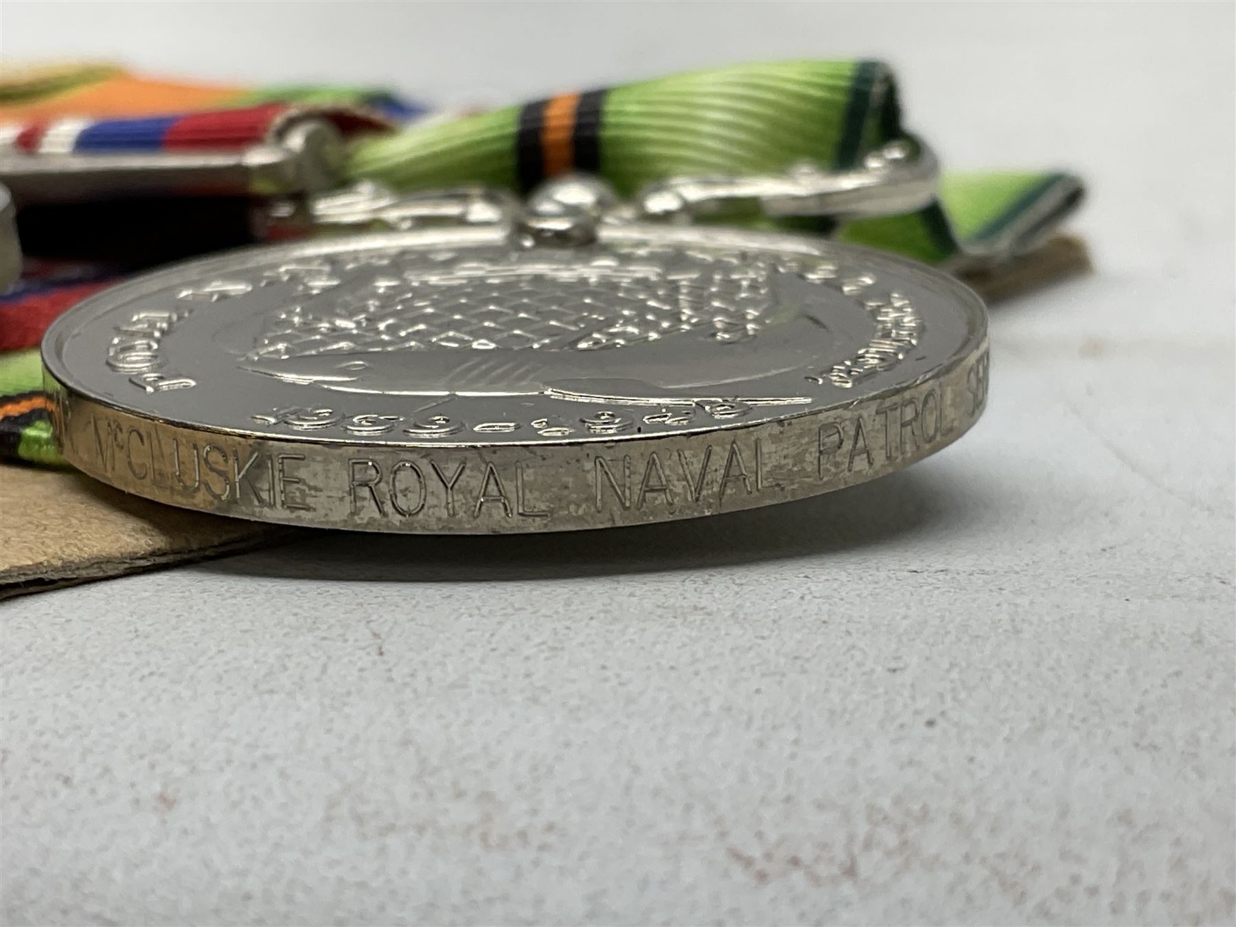 WW2 Royal Naval group of eight medals comprising OBE, hallmarked silver Distinguished Service Cross inscribed verso Lieut. J.R. McCluskie RNVR 1945, 1939-1945 Star, Atlantic Star, Africa Star, 1939-1945 War Medal, Defence Medal and Royal Naval Patrol Service Medal inscribed Lieutenant J.R. McCluskie Royal Naval Patrol Service; with seven original photographs of a sea battle 27th November 1940 against the Italian Fleet and another photographic postcard of Sir Stafford Cripps arriving on board one of the vessels.