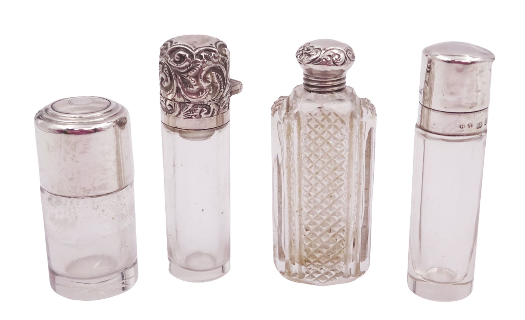 Four silver mounted glass scent bottles, including a Victorian cut glass example with embossed silver cover, and three cylindrical plain glass examples, on with engine turned decoration, three with glass stoppers, together with a pair of silver salts and spoons, all hallmarked, tallest H8cm