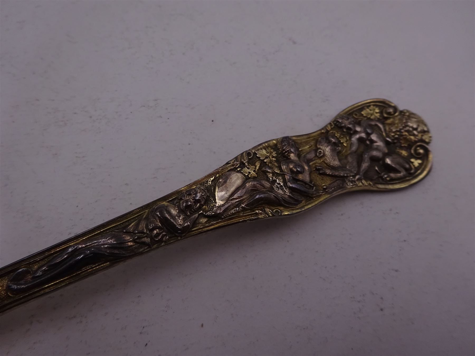 Victorian silver-gilt sugar sifting spoon, with gilded pierced shell shaped bowl, the handle decorated in relief with classical greek figures amongst fruiting vines, hallmarked Henry John Lias & James Wakely, London 1874,  L16cm, contained within tooled leather silk and velvet lined fitted case