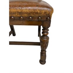 Set six Jacobean Revival oak dining chairs, back and sprung seat upholstered in tan leather with studwork border, back decorated with applied carved C-scrolls, raised on turned and carved baluster front supports united by H-stretcher