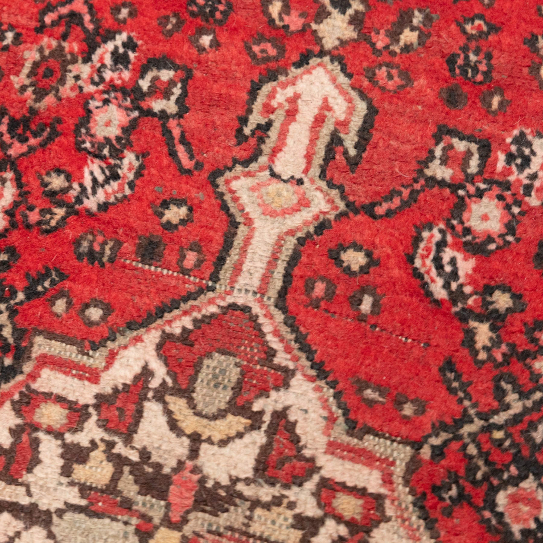 Persian crimson ground runner rug, the field decorated with repeating Herati motifs around an ivory pendant medallion, stepped ivory spandrels with stylised floral ornament, enclosed by a dark ground star border and narrow guard stripes
