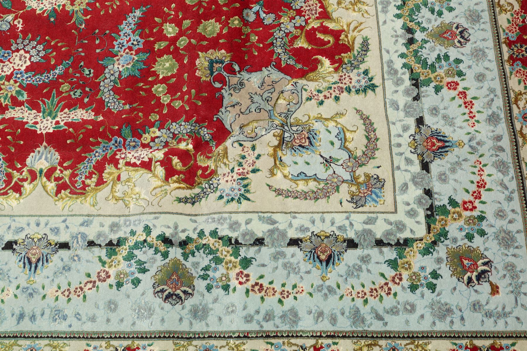 Persian silk inlaid crimson ground Kashan rug, the central shaped field with a floral pole medallion surrounded by trailing floral motifs and festoons of flowerheads, the wide cyan guard line with repeating palmettes and scrolling floral vines
